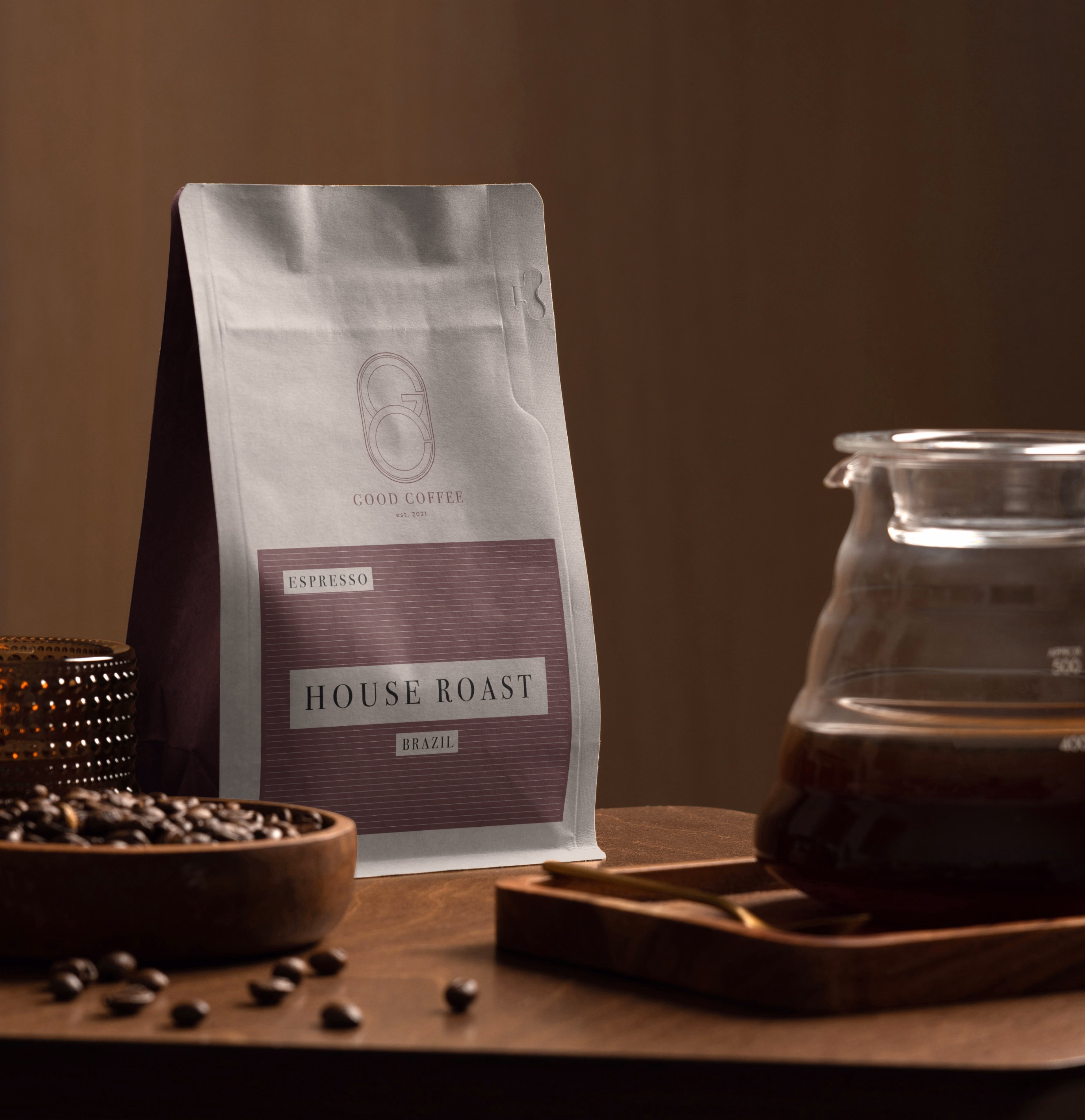 Good Coffee house roast packaging beside a glass coffee carafe and roasted beans
